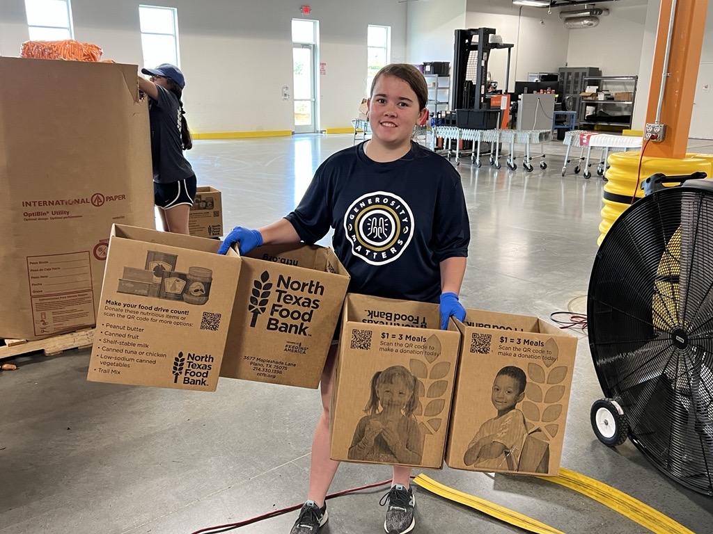 Young woman volunteer holding boxes in warehouse