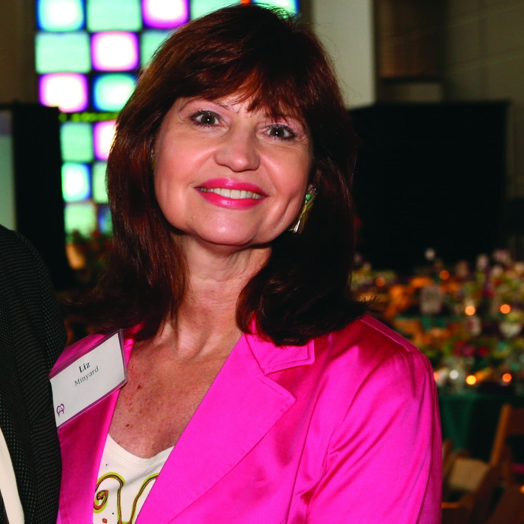 Liz Minyard Liz Minyard in a pink blazer at an event smiling