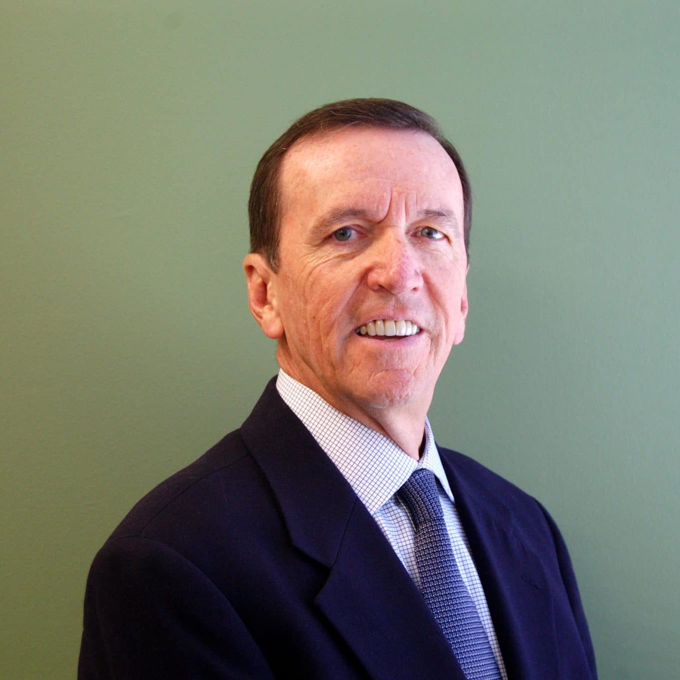 Ray Hemmig Ray Hemmig in a dark suit and tie in front of a green background