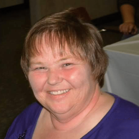 Sally Seybert White woman with short hair smiling in a purple shirt